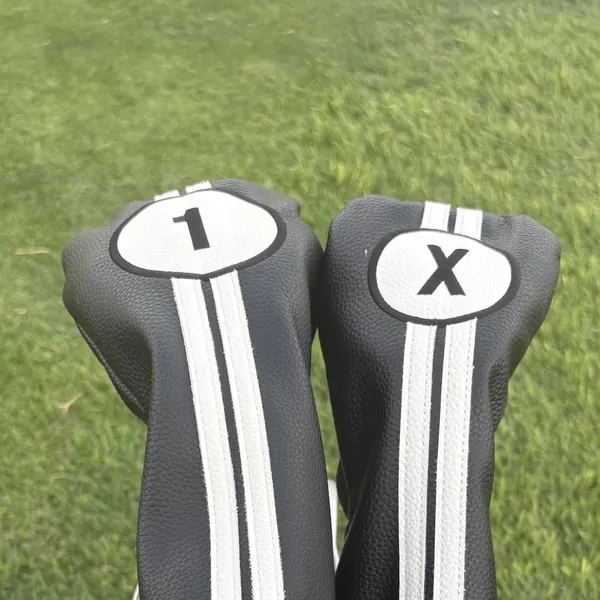 Driver and fairway wood headcovers marked 1 and X in a golf bag